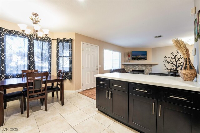 kitchen featuring an inviting chandelier, light tile patterned floors, and a stone fireplace