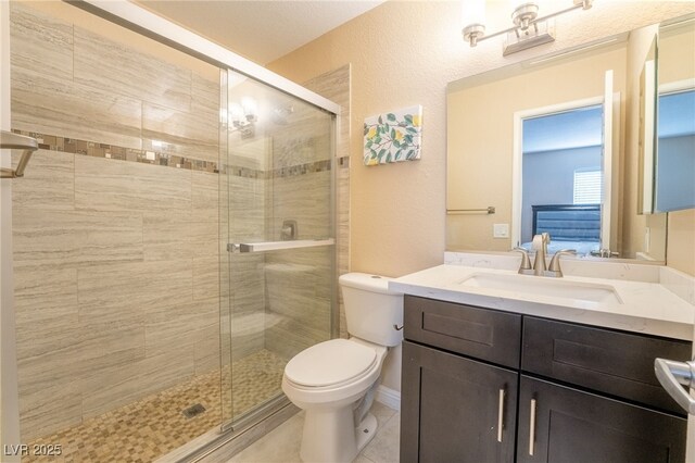 bathroom featuring toilet, a shower with door, vanity, and tile patterned floors