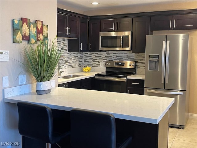 kitchen with backsplash, appliances with stainless steel finishes, light countertops, and a sink