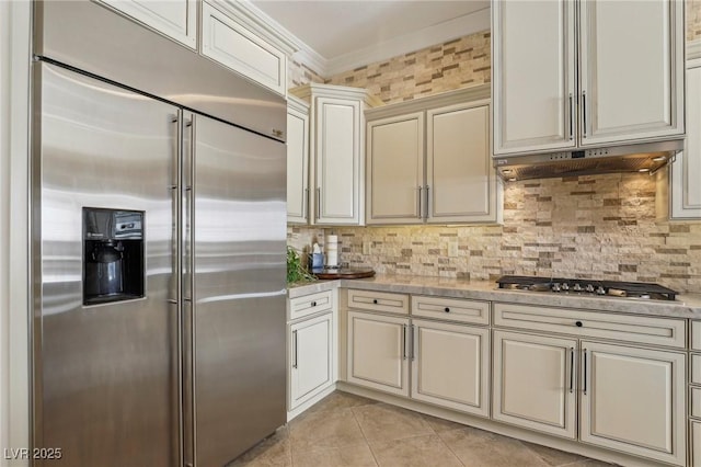 kitchen with stainless steel appliances, crown molding, light tile patterned floors, cream cabinets, and backsplash