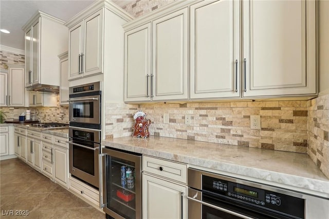 kitchen with cream cabinets, stainless steel appliances, light tile patterned floors, decorative backsplash, and beverage cooler