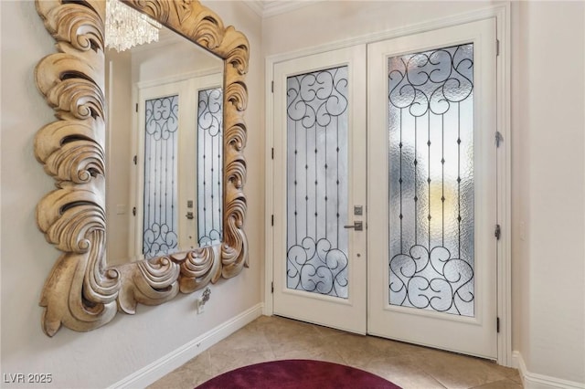 tiled entryway featuring french doors, crown molding, and a chandelier