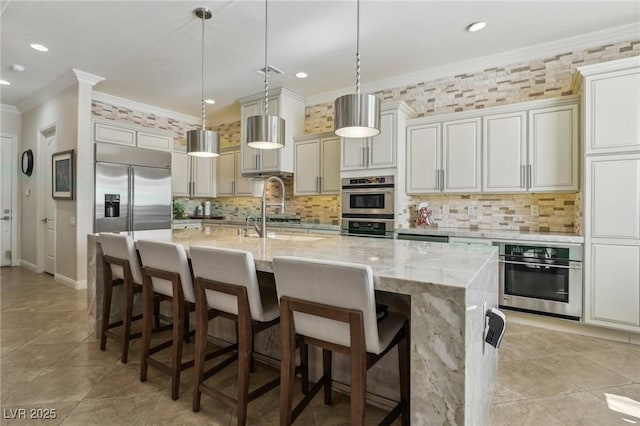 kitchen with a center island with sink, decorative light fixtures, ornamental molding, and appliances with stainless steel finishes