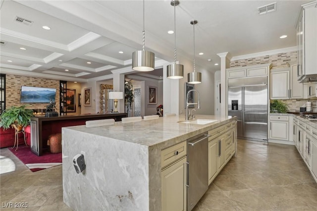 kitchen with coffered ceiling, appliances with stainless steel finishes, light stone countertops, beam ceiling, and sink