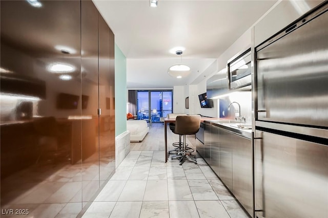 kitchen with sink, built in appliances, and a kitchen bar