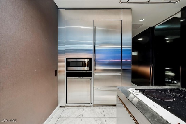 kitchen with white cabinets, stovetop, and stainless steel built in fridge