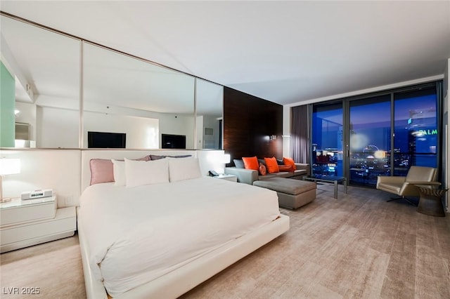 bedroom with a wall of windows and light hardwood / wood-style flooring