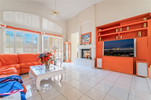 tiled living room with a high ceiling, a tiled fireplace, and built in features