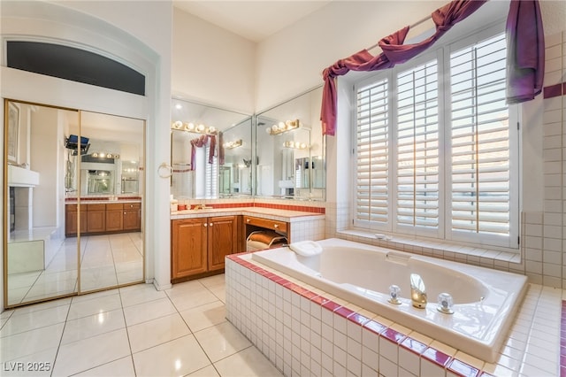 bathroom featuring a relaxing tiled tub, vanity, and tile patterned floors