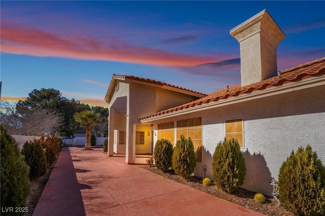 property exterior at dusk featuring a patio