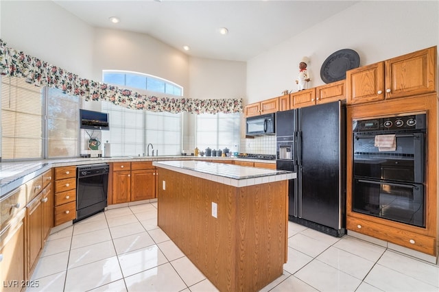 kitchen featuring black appliances, a center island, light tile patterned floors, decorative backsplash, and a high ceiling