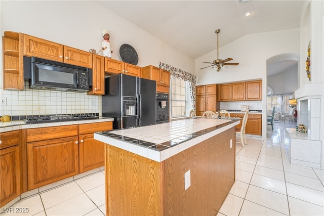 kitchen with black appliances, backsplash, a center island, and tile countertops