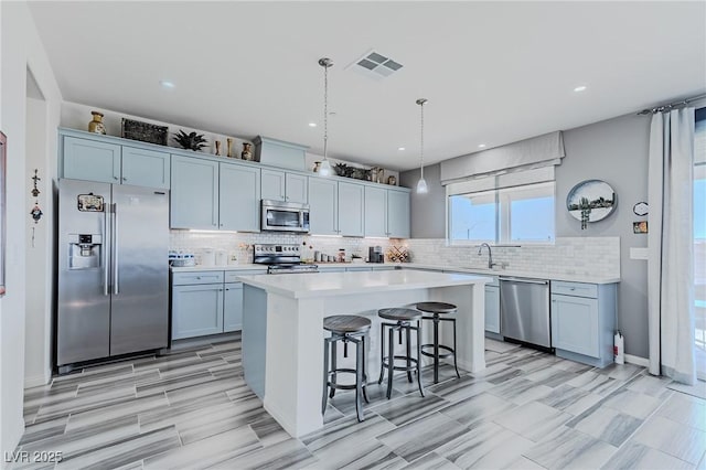 kitchen featuring hanging light fixtures, a center island, a breakfast bar area, appliances with stainless steel finishes, and sink