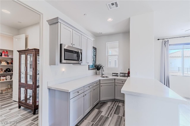 kitchen with sink, gray cabinets, and kitchen peninsula