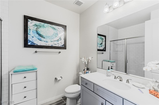 bathroom featuring toilet, vanity, and a shower with shower door