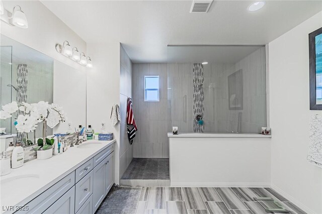 bathroom with a tile shower and vanity