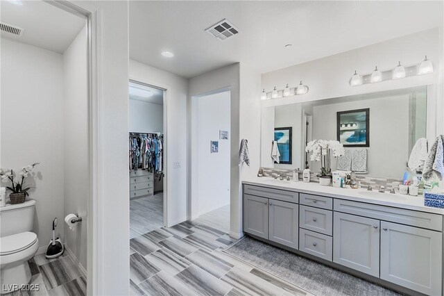 bathroom with toilet, wood-type flooring, vanity, and tasteful backsplash