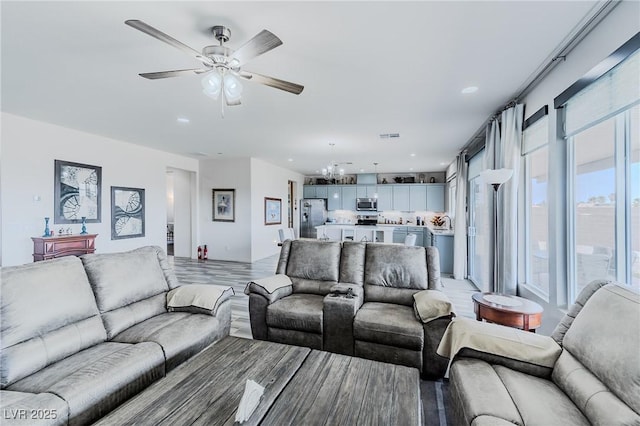 living room with light hardwood / wood-style floors and ceiling fan with notable chandelier