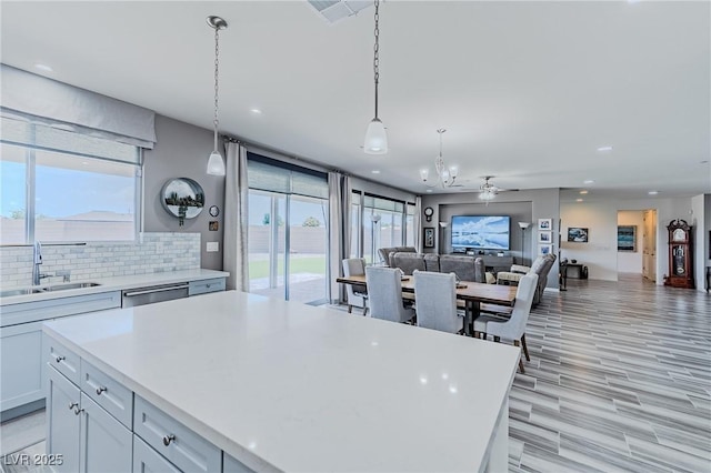 kitchen featuring sink, decorative backsplash, a center island, and ceiling fan