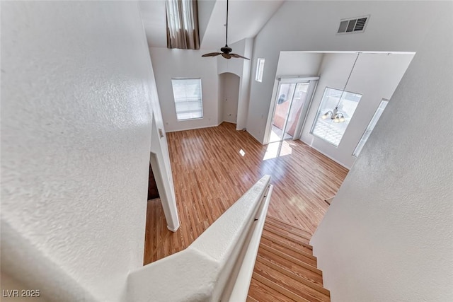 foyer featuring a towering ceiling, ceiling fan with notable chandelier, a wealth of natural light, and hardwood / wood-style floors