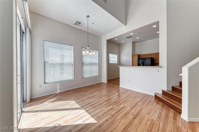 unfurnished living room featuring light hardwood / wood-style floors and an inviting chandelier