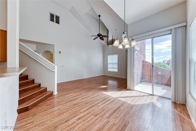 interior space featuring ceiling fan with notable chandelier, high vaulted ceiling, and light hardwood / wood-style floors