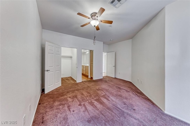 unfurnished bedroom featuring a spacious closet, connected bathroom, light carpet, ceiling fan, and a closet