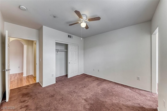 unfurnished bedroom featuring dark carpet, a closet, and ceiling fan