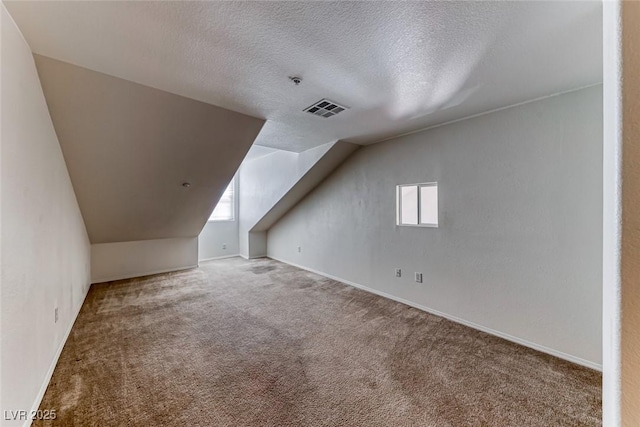 bonus room with a textured ceiling, lofted ceiling, plenty of natural light, and carpet flooring