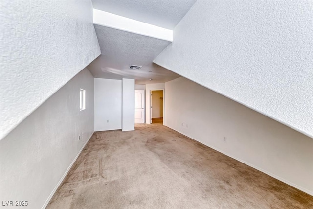 bonus room with a textured ceiling, vaulted ceiling, and light colored carpet