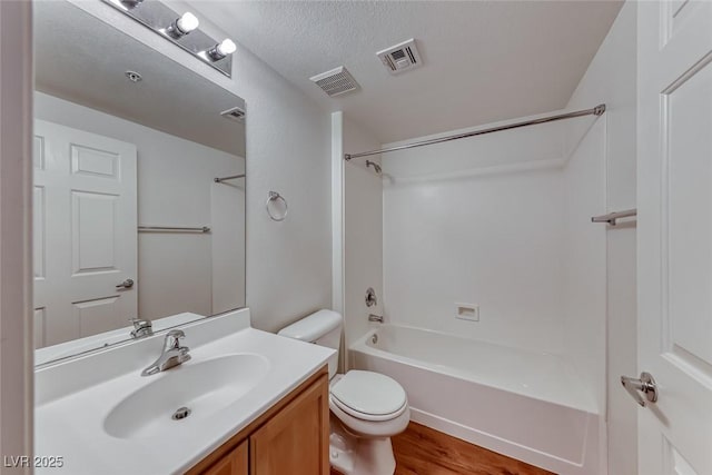 full bathroom featuring bathtub / shower combination, toilet, vanity, hardwood / wood-style flooring, and a textured ceiling