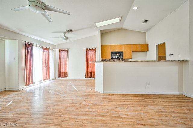 interior space with ceiling fan, lofted ceiling with skylight, and light wood-type flooring