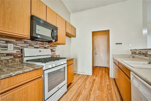 kitchen featuring light wood-type flooring, sink, tasteful backsplash, and white appliances