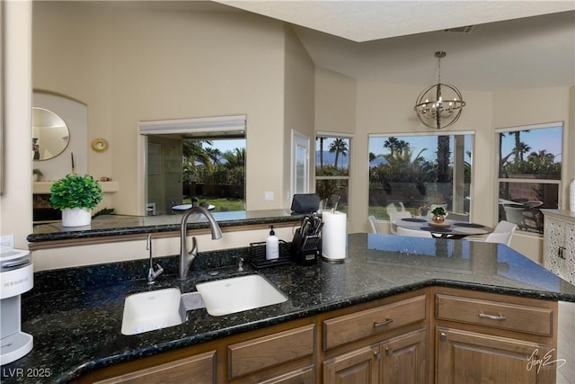 kitchen featuring hanging light fixtures, an inviting chandelier, a wealth of natural light, and dark stone countertops