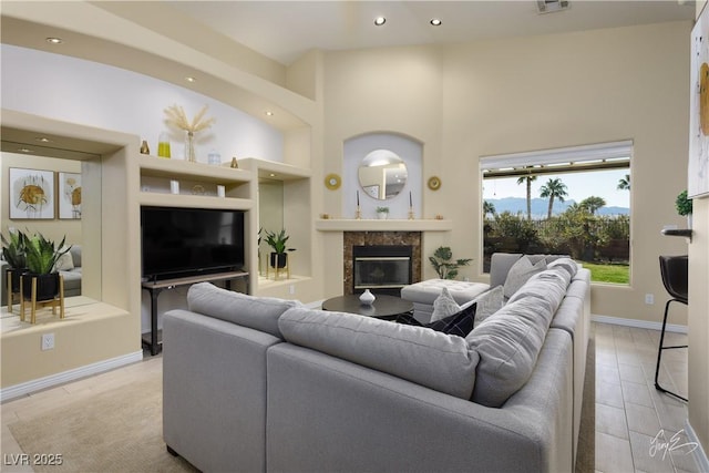 living room featuring built in shelves, a premium fireplace, and light hardwood / wood-style flooring