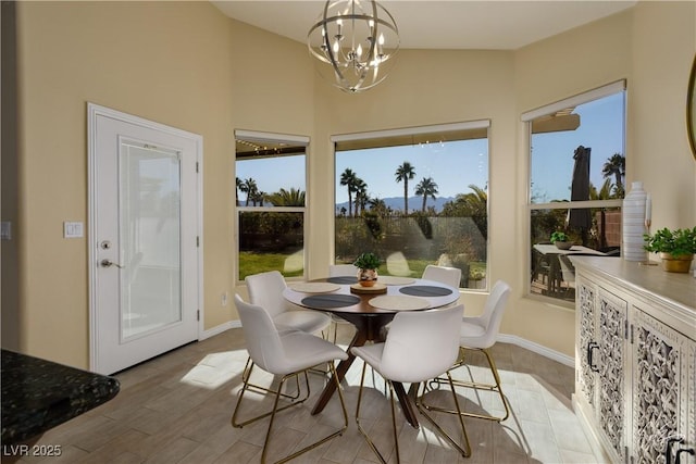 dining room with light hardwood / wood-style floors, a notable chandelier, and vaulted ceiling