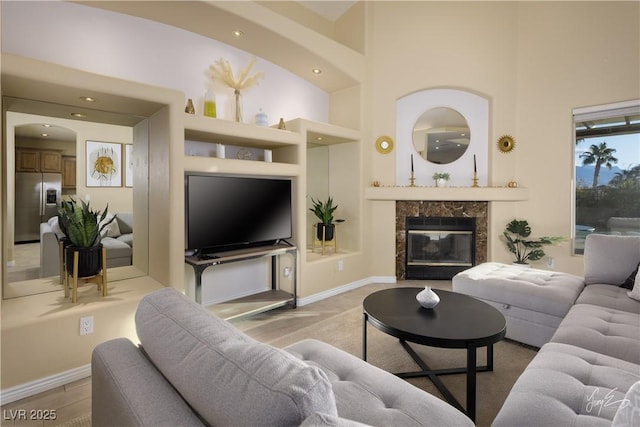 living room with a high ceiling, built in shelves, and a fireplace