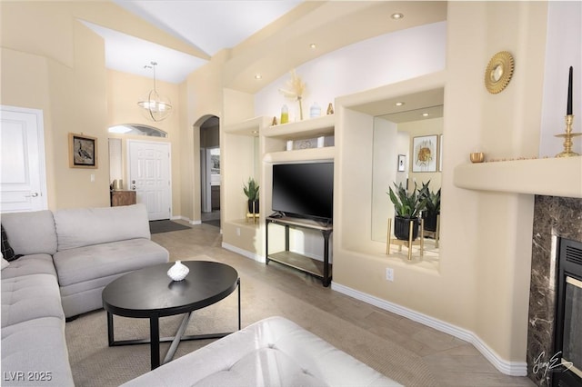 living room featuring lofted ceiling, a high end fireplace, and built in shelves