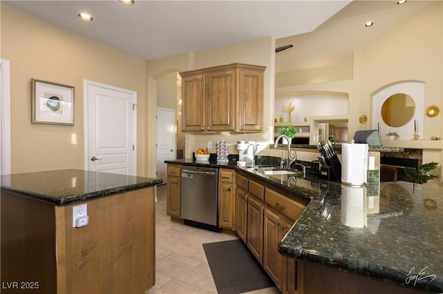 kitchen with kitchen peninsula, stainless steel dishwasher, a kitchen island, dark stone countertops, and sink