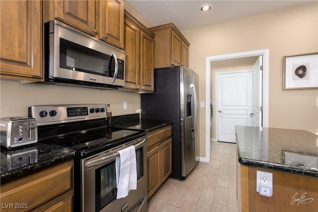 kitchen with stainless steel appliances and dark stone countertops