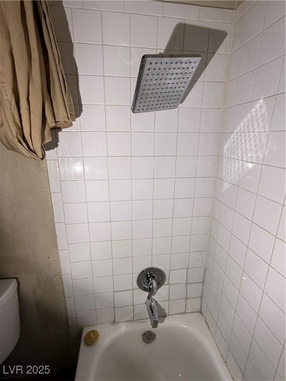 bathroom with toilet and tiled shower / bath combo