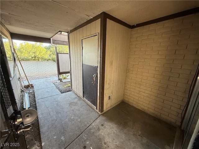 interior space with brick wall, wood walls, and concrete flooring