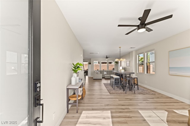 dining area with ceiling fan with notable chandelier and light wood-type flooring