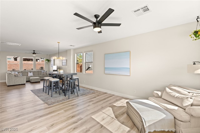 dining room with light wood-type flooring and ceiling fan with notable chandelier