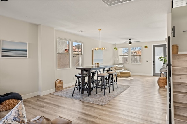 dining area with light hardwood / wood-style flooring and ceiling fan with notable chandelier