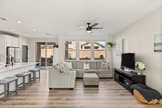 living room with sink, ceiling fan, and light hardwood / wood-style flooring