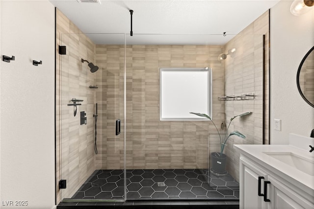 bathroom with a shower with shower door and vanity