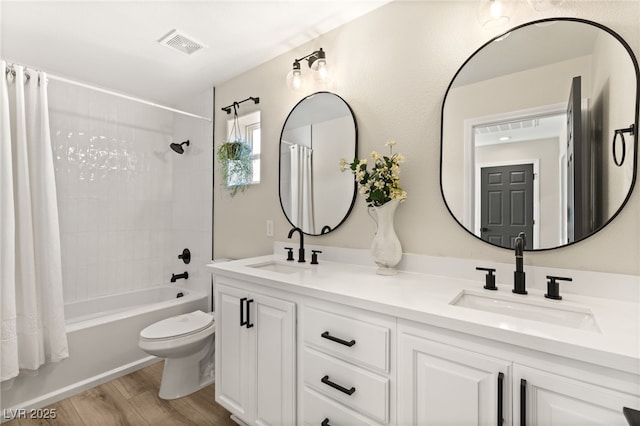 full bathroom featuring vanity, hardwood / wood-style floors, shower / bath combo with shower curtain, and toilet