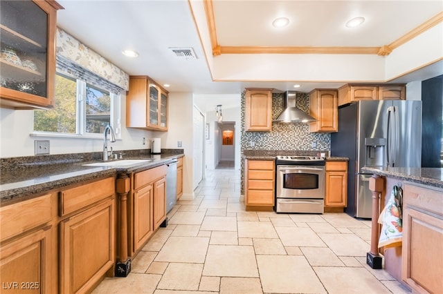 kitchen with sink, dark stone countertops, wall chimney range hood, crown molding, and appliances with stainless steel finishes