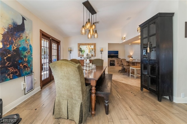 dining area with french doors, a notable chandelier, and light hardwood / wood-style flooring